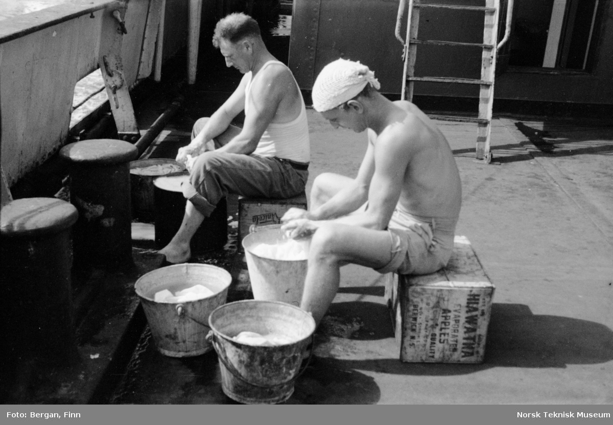 To personer sitter på skipsdekk og vasker i bøtter