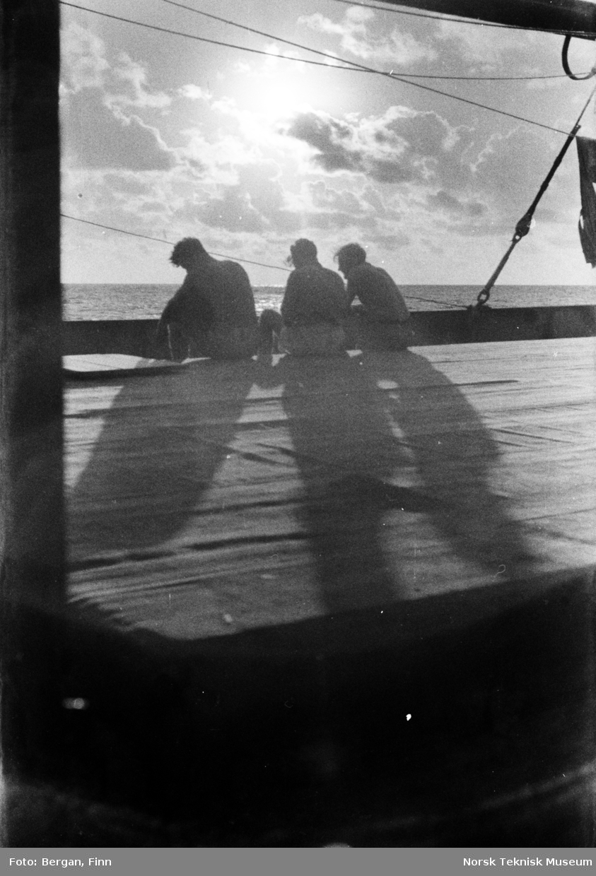 Sol og skyer, trepersoner i motlys, på skipsdekk
