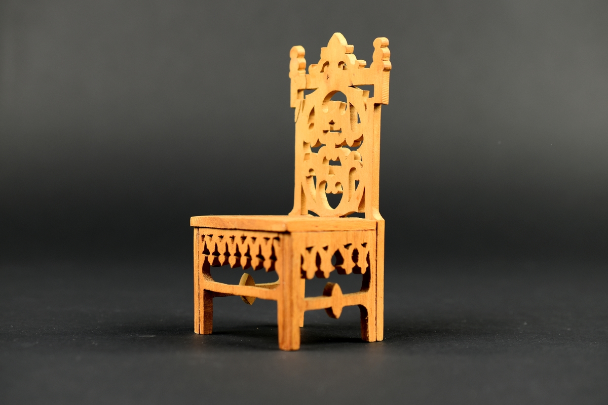 En av två stolar tillverkade av cigarrlåda, med genombruten dekor i sits, rygg och sarg.