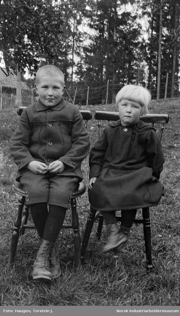 Portrett to barn, Olav og Anlaug Skogen, sittende på stoler.