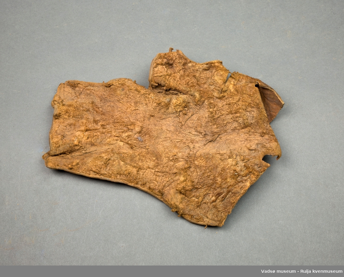 Et stykke garvet skinn, ca. 25 x 25 cm. Uregelmessig rektangulær form med skjærte kanter.