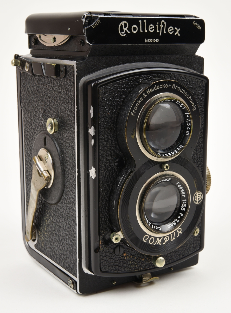 En tvåögd spegelreflexkamera av typen Rolleiflex (:1) med tillhörande beredskapsväska gjord av brunt läder (:2).

Det översta objektivet (som används för att komponera bilden) i kameran är ett Heidoscop-Anastigmat 75mm f 3,1. Det nedersta objektivet som används för att ta själva bilden är ett Carl Zeiss Jena modell Tessar 75mm f 3,5. Kameran är gjord i metall och är dekorerad med konstläder / läderimitation.

Den bruna beredskapsväskan (:2) har på baksidan ett fönster av gulnad plast som är till för att kunna läsa exponeringstabellen på kamerans baksida.

Kameran tar 120 film.