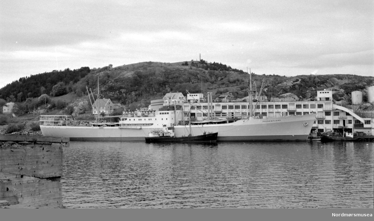 Foto av fartøyet "Foldenfjord" ved ESSO's anlegg i Kristiansund. Datering er usikker, men kan være i 1959. Fotograf er Nils Williams. Fra Nordmøre museums fotosamlinger.