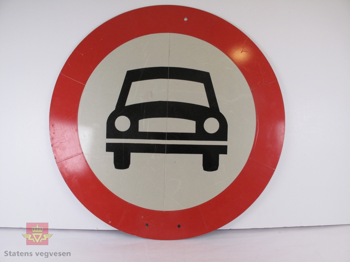 Sirkelformet skilt med rød bord (7,5 cm). Bunnen er hvit og lysreflekterende, og har figur av en bil i svart. Skiltet betyr at det er "forbudt for motorvogn som har flere enn to hjul".