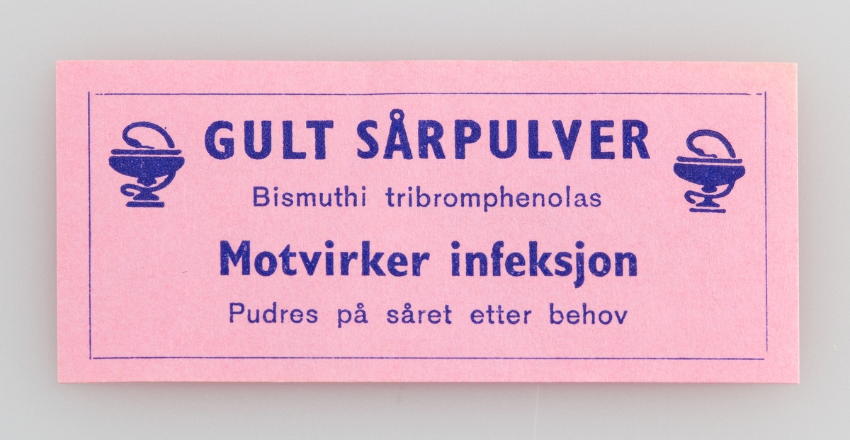Etikett til preparat til utvortes bruk. Dekorert med emblemet til Norges Apotekerforening. Lim på baksiden