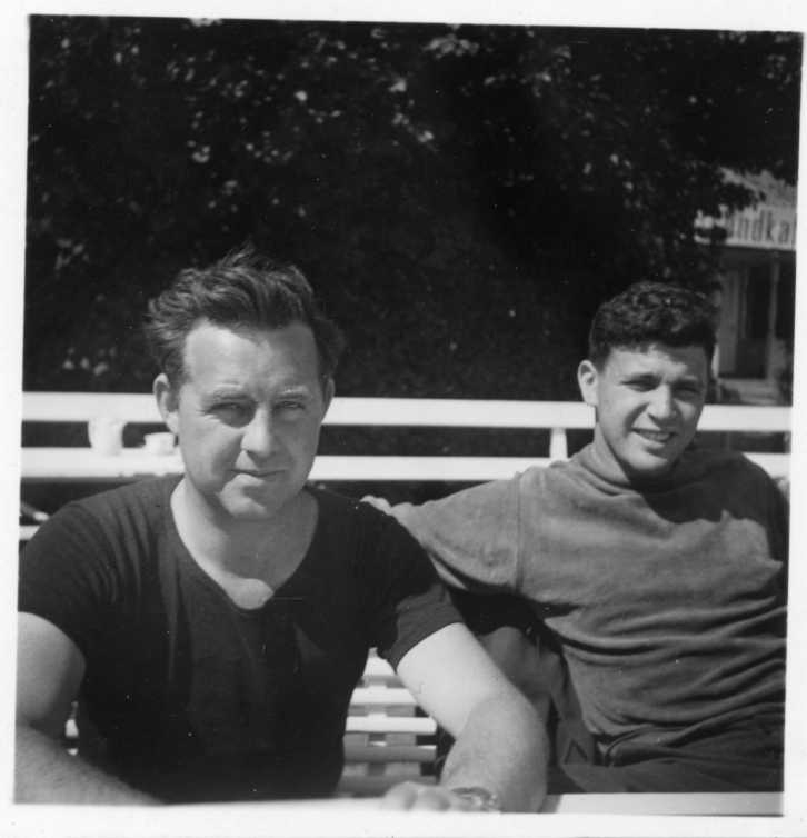 Två män sitter i en trädgårdsmöbel, en i t-shirt lutad mot bordet och den andra lutad bakåt mot stolsryggen. Det är möjligen Janeczek och Ponke.