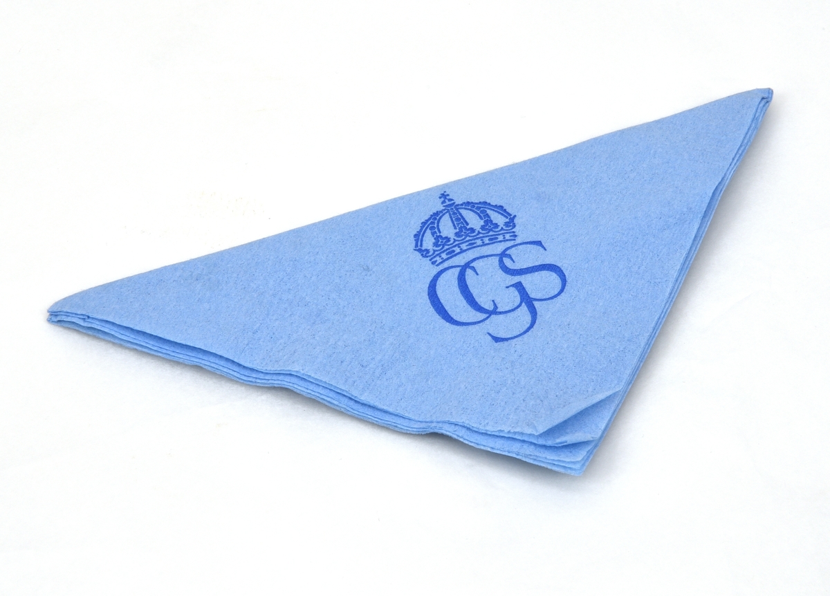 Ljusblå kvadratisk pappersservett med det monogram som användes vid kungabröllopet 1976 tryckt i mörkblått. Monogrammet består av "CGS" med en kunglig krona ovanför. Runt servettens kanter går en streckad bård med pärlstavsfris.