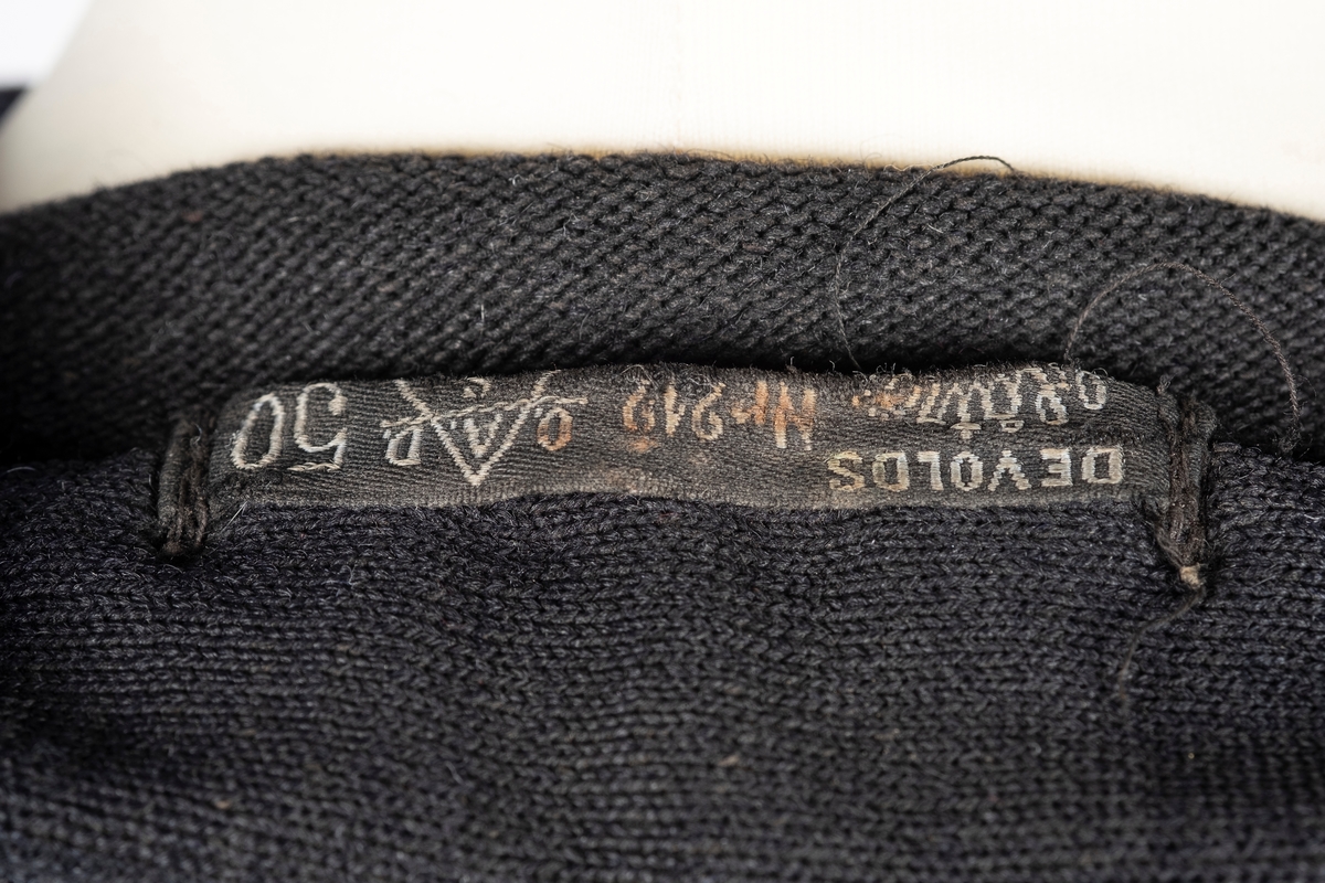 En sort langermet genser med krage og glidelås i genserens øvre del. To lommer med klaff på hvert brystparti. Nummeret: 808, er brodert inn over genserens høyre brystlomme.