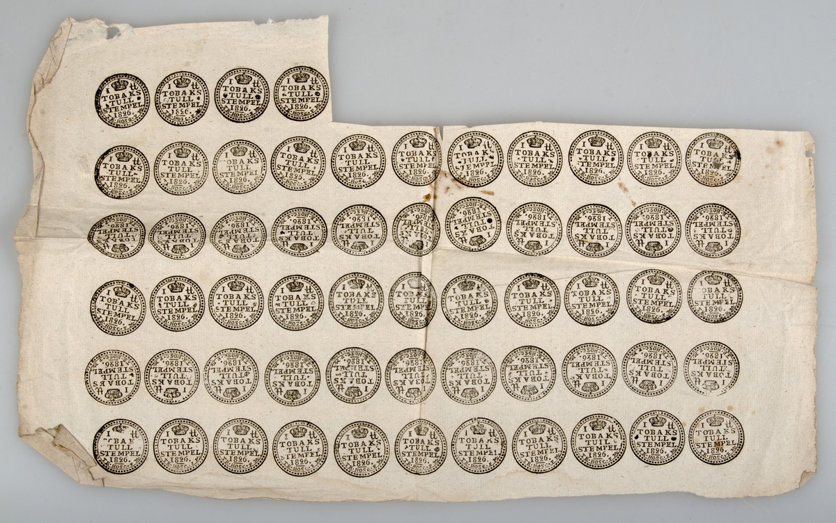Två kartor med tobakstullstämplar, tryckta på papper. Stämpelns text: TOBAKSTULLSTEMPEL 1826. Den ena kartan hel med 66 stämplar, på den andra är 7 stämplar bortklippta.