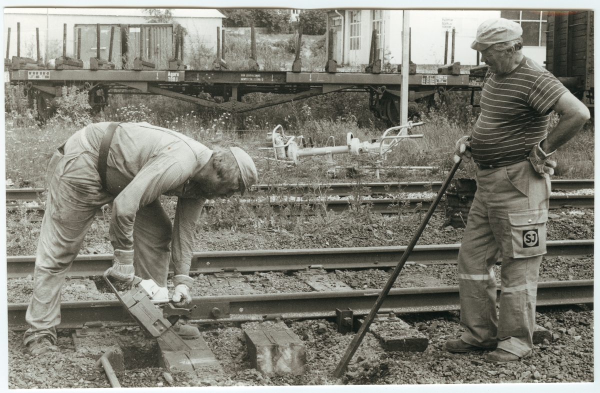 Banarbetare vid Statens Järnvägar, SJ sågar av sliprar på bangården i Lindesberg.