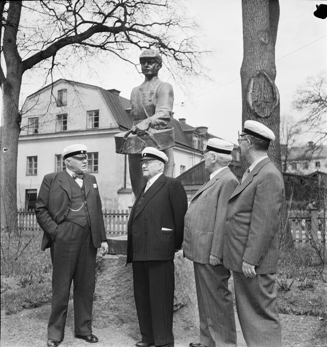 Äldre studenter står vid statyn Såningsmannen i trädgården på Östgöta nation, Uppsala 1 maj 1954
