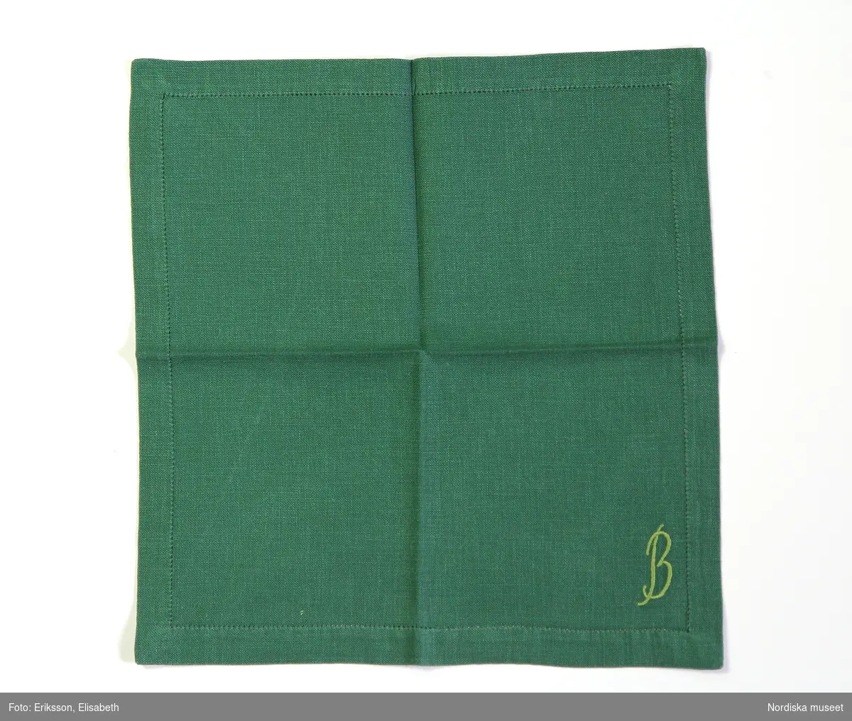 Servett av grönt linne med monogram B broderat i ljusgrön plattsöm.