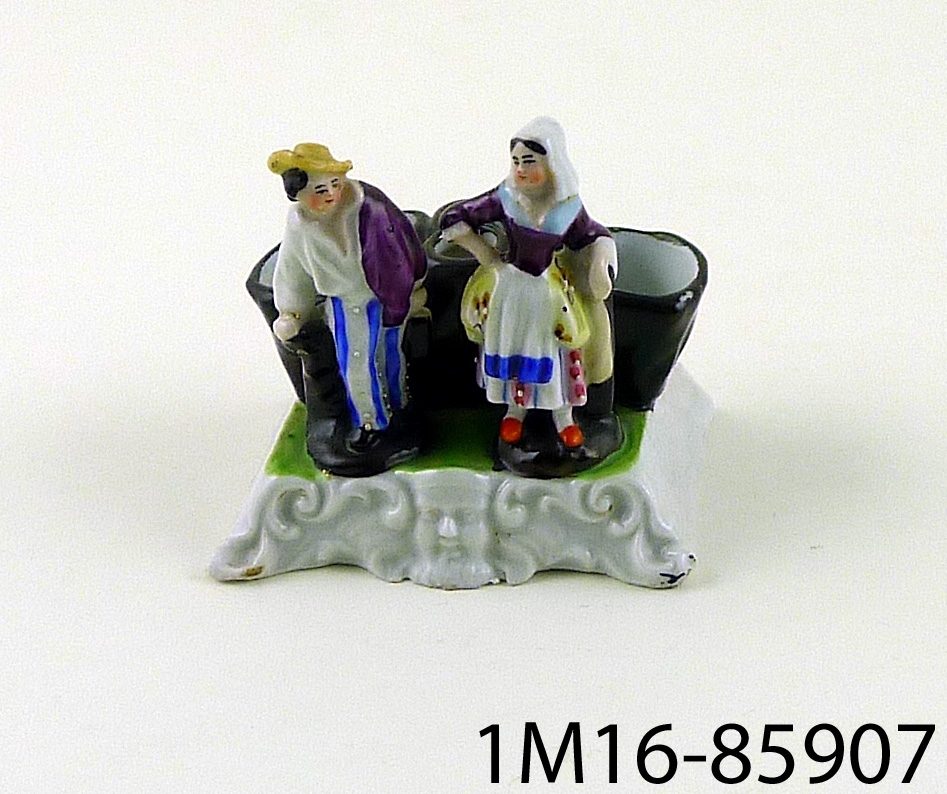 Figurin föreställande en kvinna och en man stående framför tre stycken behållare för blommor.