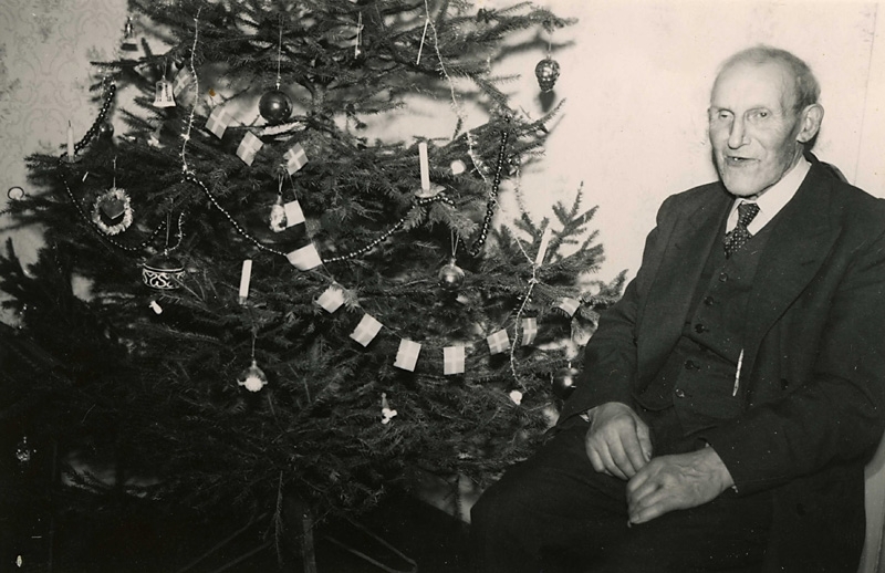 Robert Pettersson sitter vid en julgran, Brattåshemmet okänt årtal. Född 1886 i Lindome, död 1968 på Brattåshemmet i Kållered. Arbetade som dräng på Ekans gård i många år.