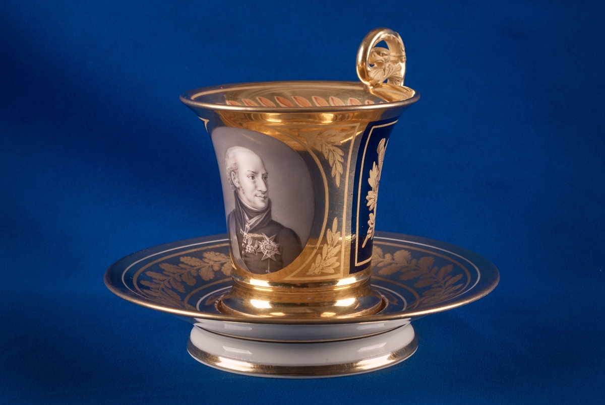 Karl XIII:S kopp.
Kopp med fat från Daite Freies i Paris, omkring 1800.
Koppens höjd 9.5 cm. Fatets diameter 16,5 cm.
Koppen bär på ena sidan Karl XIII:s bild och är på motstående sida dekorerad med ett par antika hjälmar.
Dekor i empirestil i guld och blått.
En grepe med örnhuvud och palmettdekor. Fatet är dekorerat med en eklövskrans.