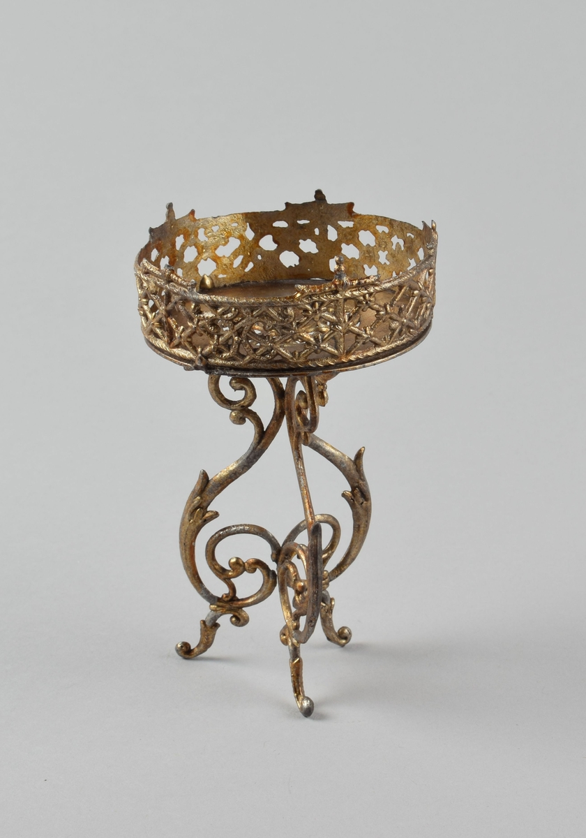 Lite rundt blomsterbord i gjennombrutt metall på tredelt ornamentert fot.