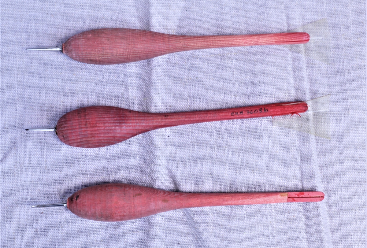 Tre rødmalte trepiler med metallspisser. Gjennomsiktige plastikkvinger på pilene (a) og (b), mangler på (c).