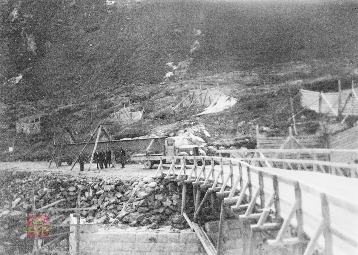Gamle Skjøyten (Skjøiten) bru på Rv 52, Hemsedalsvegen, ble i 1938 erstattet med ny stålbjelkebru. Mursteinen til landkar ble sprengt og kilt ut ved Svøo både til Venås og Skøyten bru. Stålbjelkene var 21 meter lange og 1 meter høye. Hver bjelke veide 6,7 tonn. Her fra transport av stålbjelke som startet på Gol jernbanestasjon. Olav E Fekene som kjørte en GMC 1935 modell lastebil med registreringsnummer F13065 hadde fått oppdraget. Her er transporten framme ved bru-stedet og første bjelke skal lastes av.
