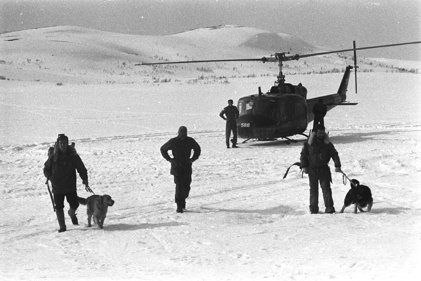 Lavinehunder og førere, med et av luftforsvarets helikopter i bakgrunnen.