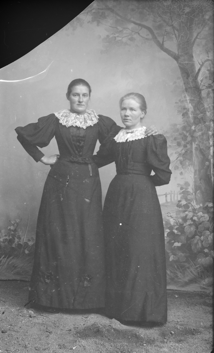 To kvinner med mørk, sid kjole og store blondekrager