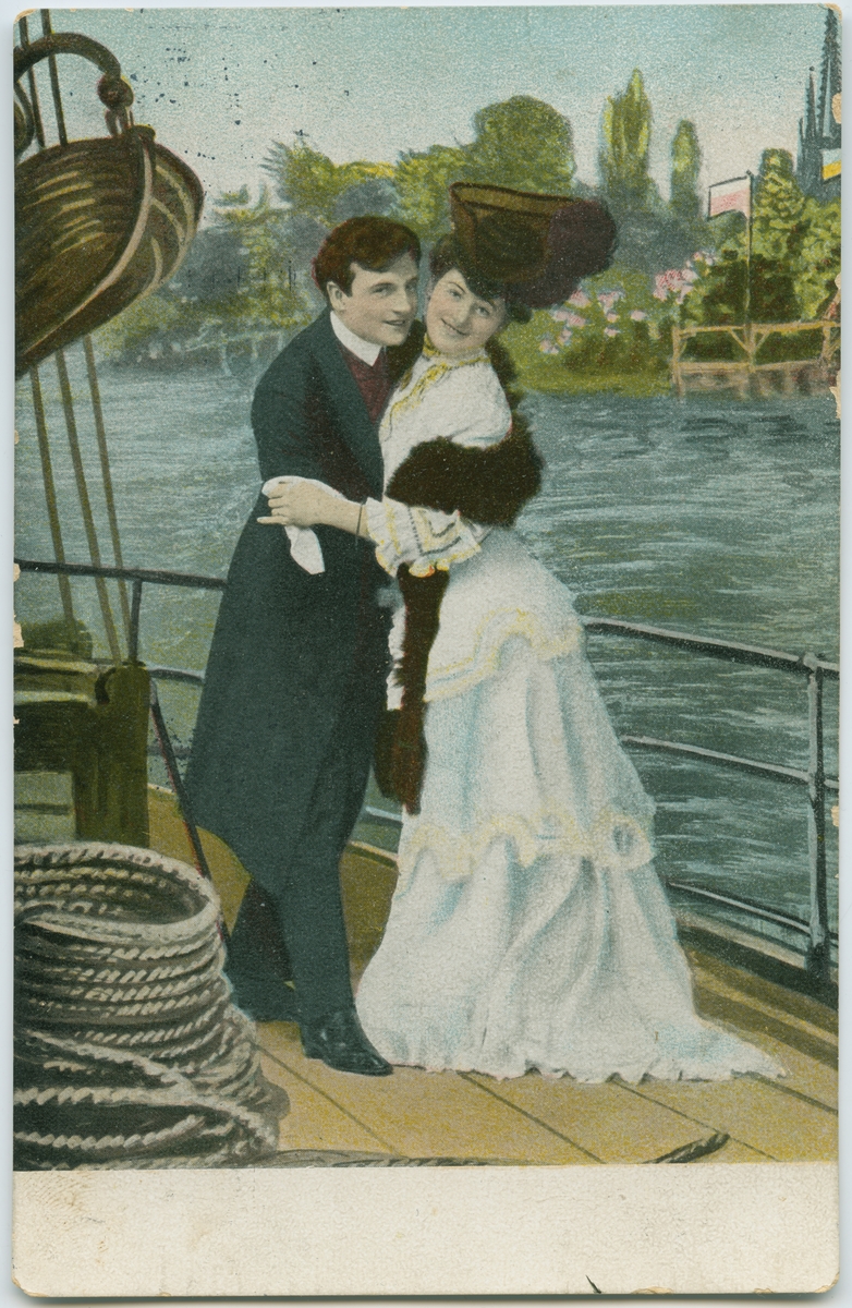 Postkort. En man och en kvinna står och omfamnar varandra på däck. De tittar leende in i kameran