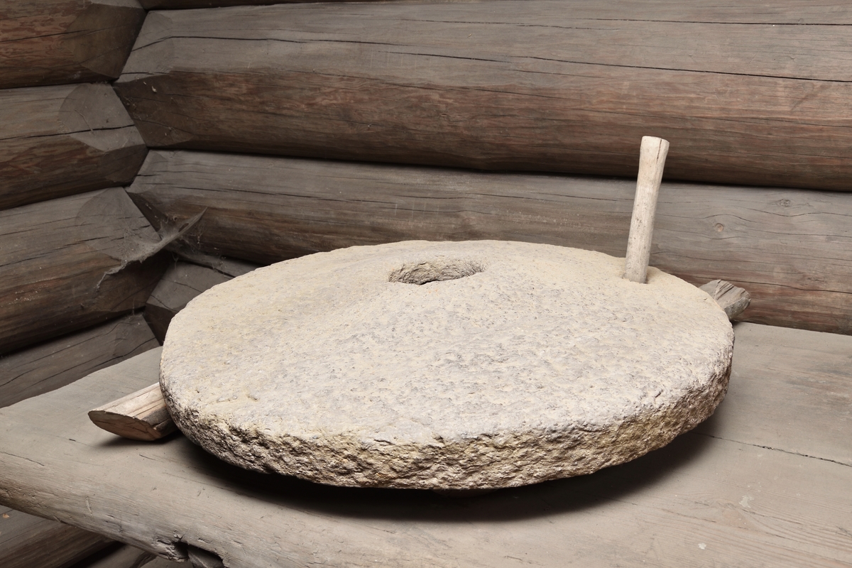 Handkvarn i form av en rund sten, välvd, samt ett runt hål mitt i. Segel av trä, rektangulärt med hål. Sekundärt draghandtag. Underliggare saknas.