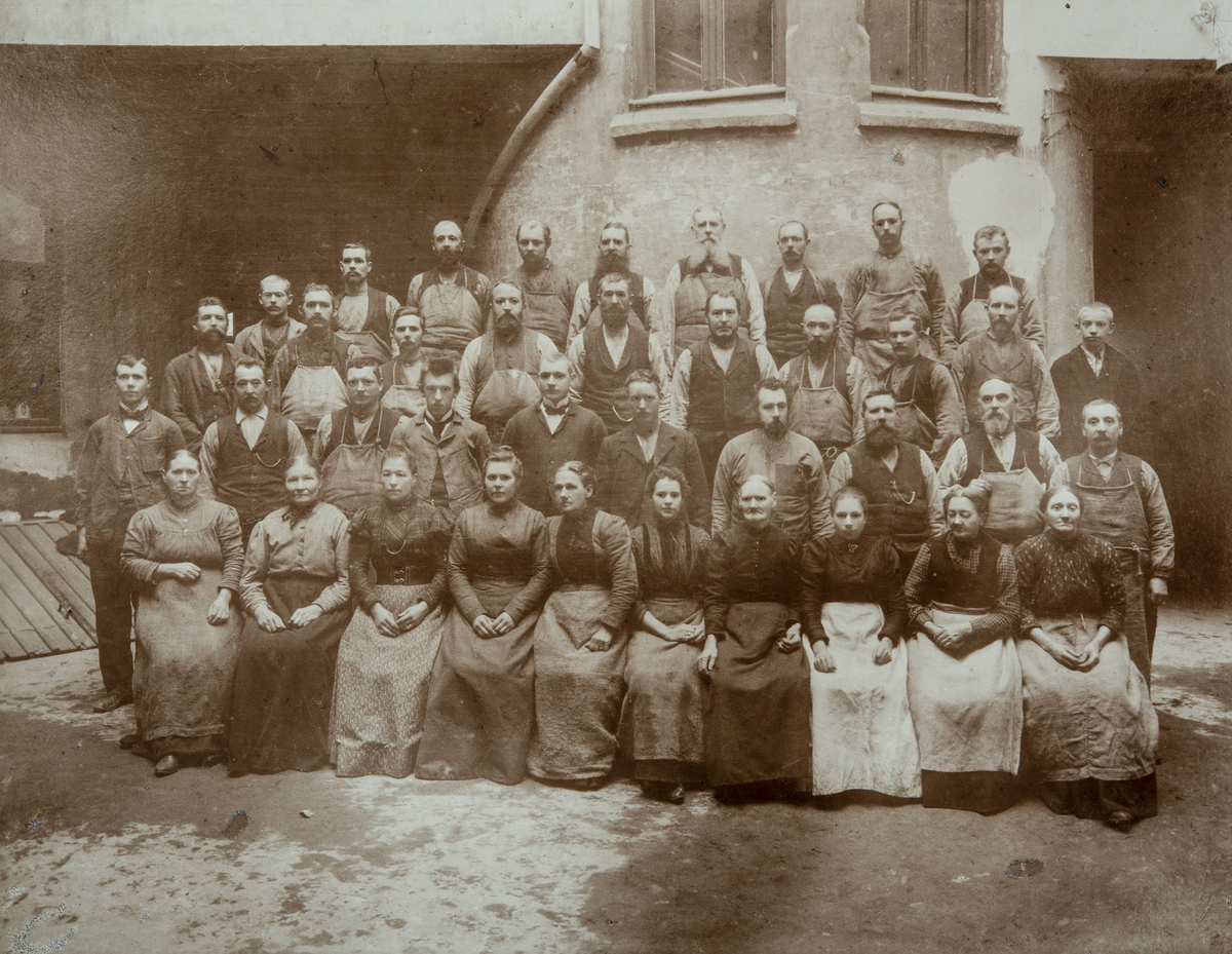Arbeiderne i H.Poulsen & Co, Dronningensgade 36, Christiania (1905). 
Avbildet er tappere, lagerarbeidere og skyllekoner. Kontorpersonalet og kjørere er ikke med på bildet. 
