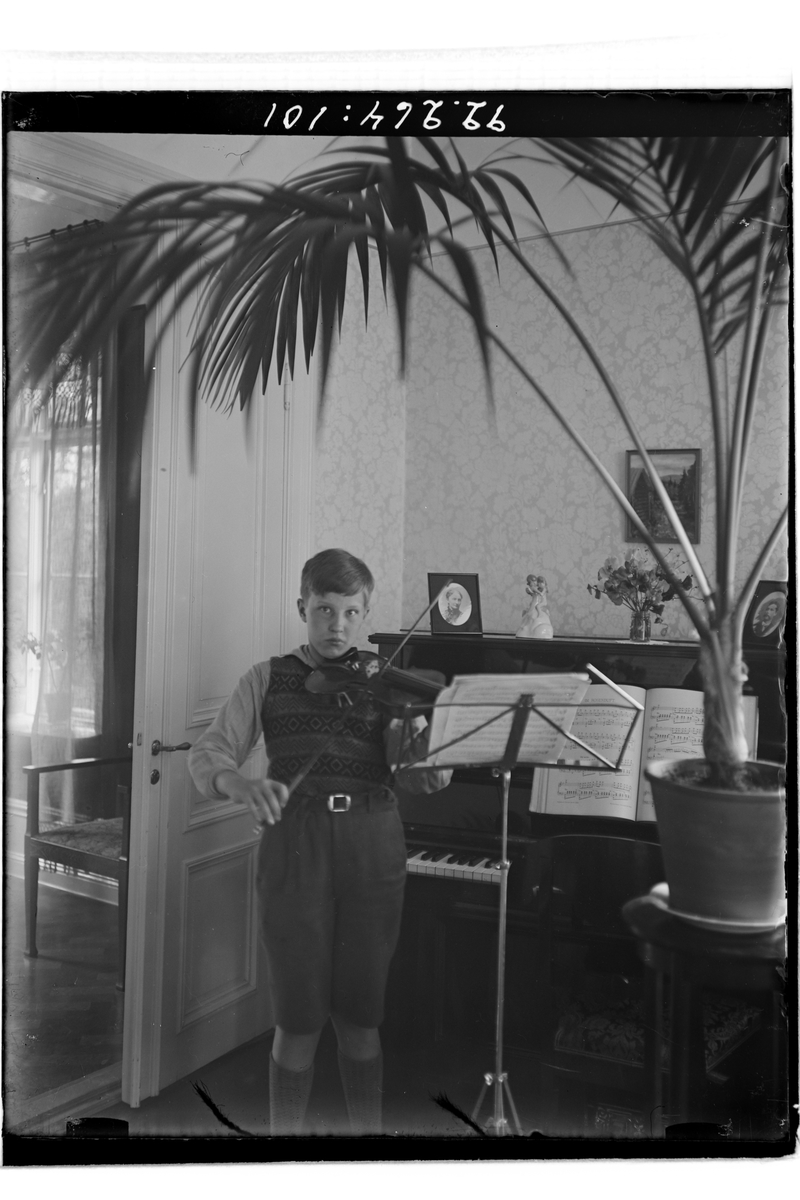 Hålahults sanatorium, interiör, pojke med fiol stående vid piano, stor palm i förgrunden.