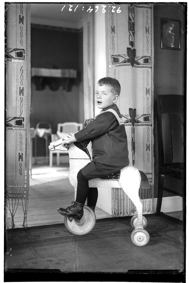Hålahult sanatorium, interiör, pojke klädd i sjömanskostym på en trähäst med hjul.