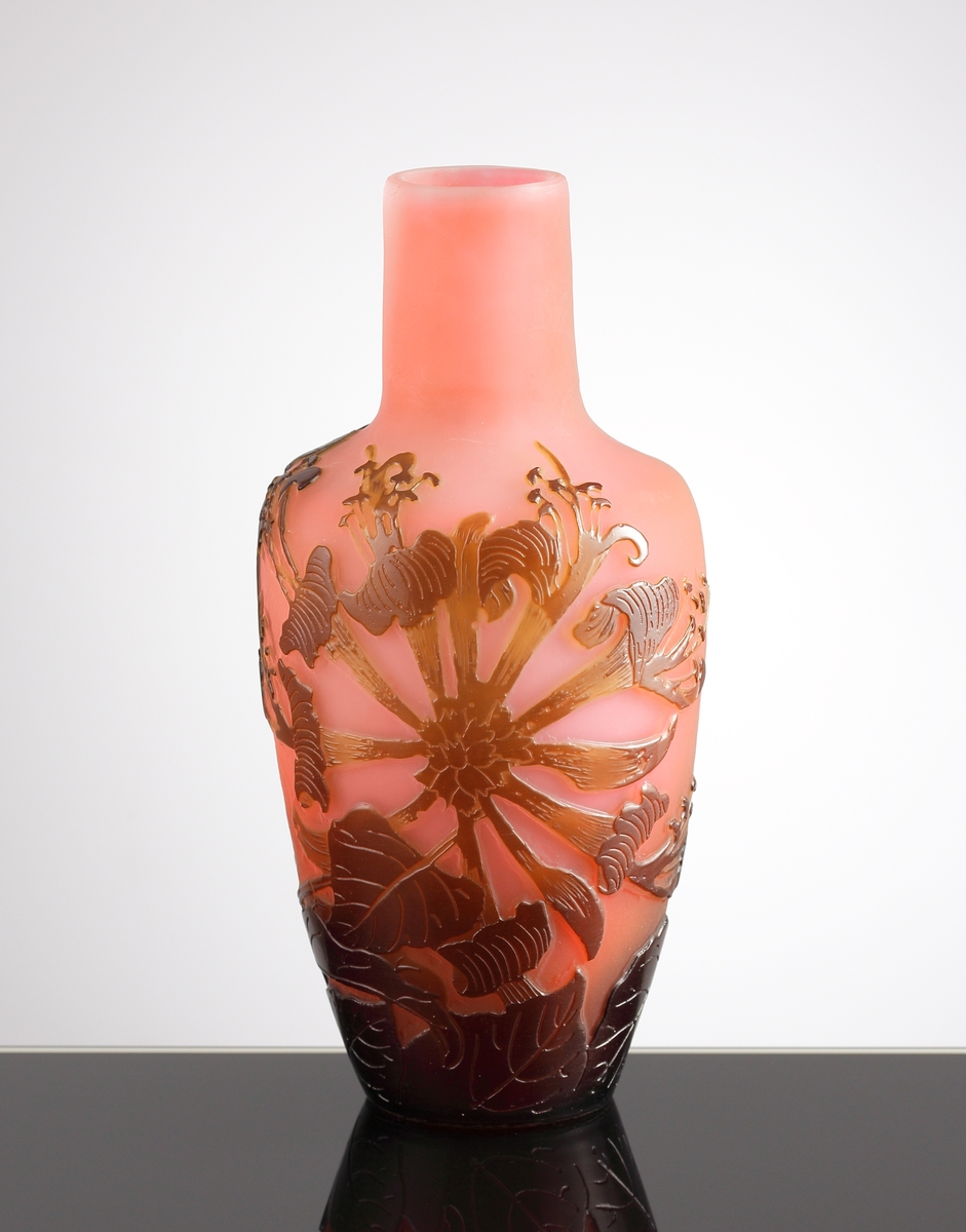 Röd opak vas med blomstermotiv i brunrött etsat överfång.