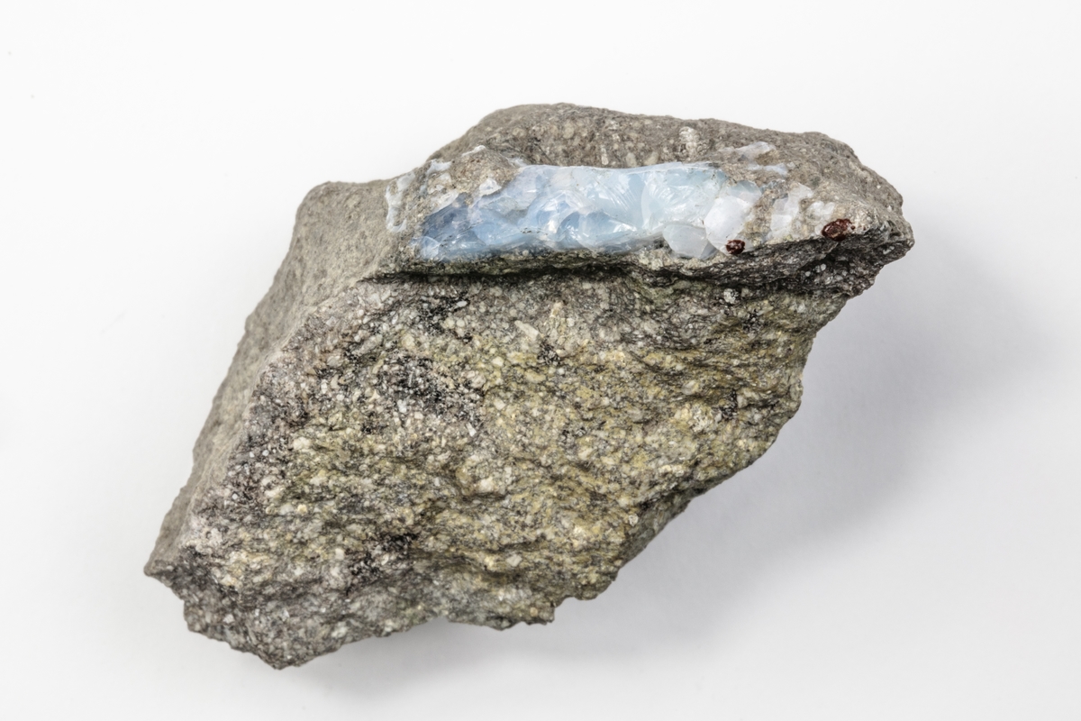 Ett mineral som är en opal och består av vattenhaltig kiseldioxid. Färgen kan variera mellan vit, grå, blå, grön, orange och svart. Detta exemplar är ljusblått. Exemplaret kommer från dåvarande Österrike/Ungern och ingår i Adolf Andersohns samling.