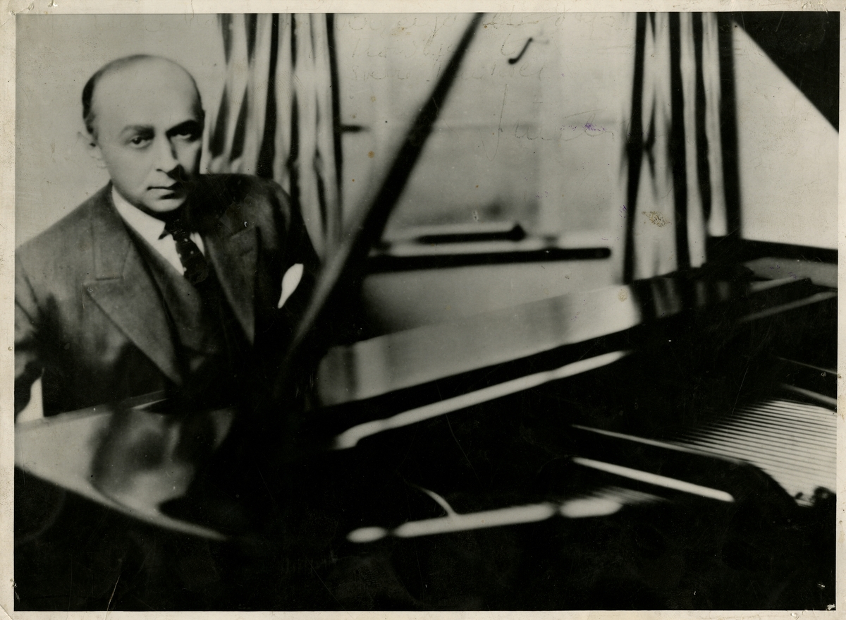 Fra Olaf T. Ranum's "kunstnervegg". Bildet viser pianist Jan Smeterlin ved et flygel.
Tekst på baksiden: Født i Ploen. Britisk borger.
