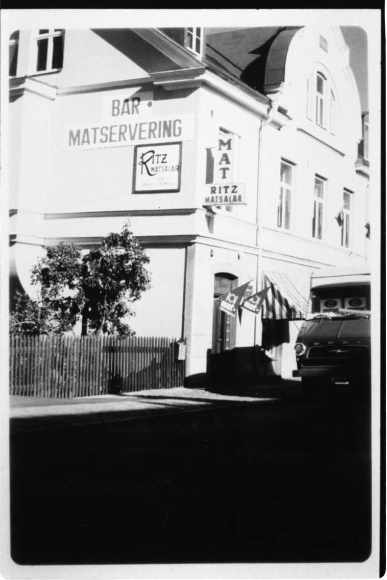 Brahegatan 3 från sydöst i starkt solljus. På väggen skylt: "Bar Servering Ritz Matsalar".