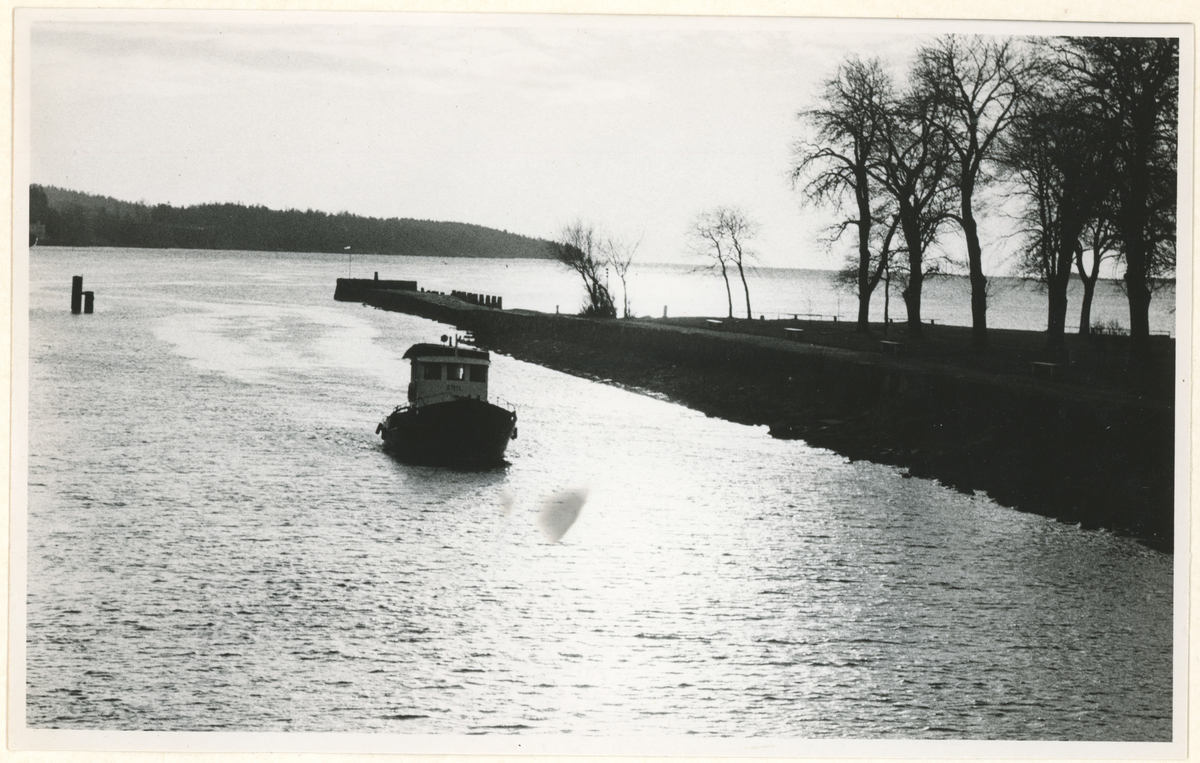 Foto er tatt fra kanalbroen, utover moloen.
Detaljer: "Emil", en isbrøyter og slepebåt i kanalen.
Historikk: Emil ble bygget i 1954, og arbeidet i hele Oslofjorden. Hovedbase i Moss. Badehuset ble tatt ned i 1970, og fyret i 1969.

