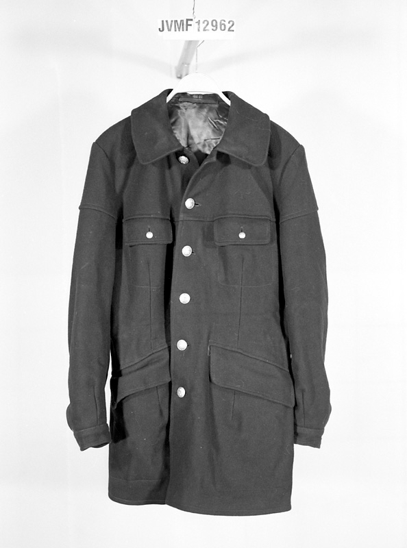 Enkelknäppt jacka av mörkblått kläde med knappar modell 1953. Jackan har två snedställda framfickor med lock, samt två bröstfickor med lock med knäppning. Den har nedliggande krage och ärmar med manschett.