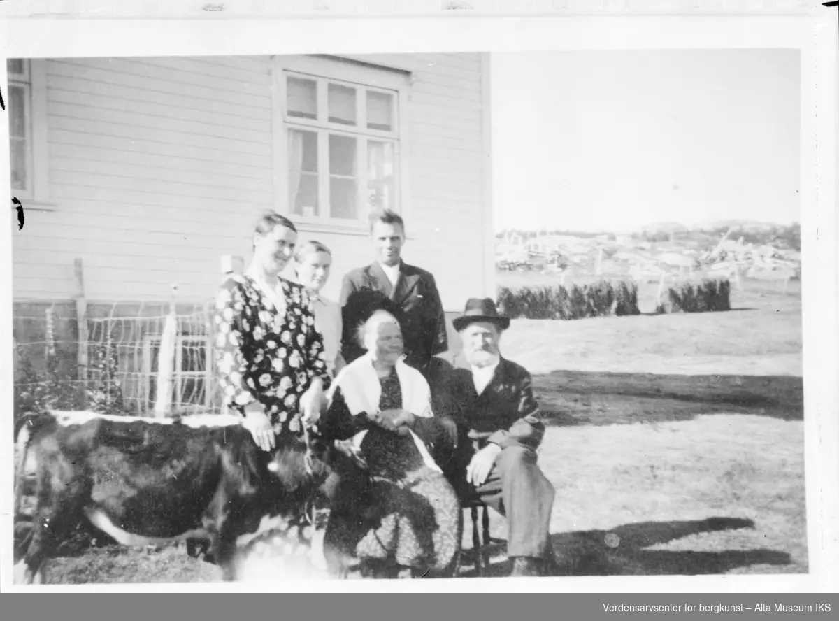 Gruppebilde av 5 personer med en kalv eller et esel fotnan et hvit hus på Årøya 1939.