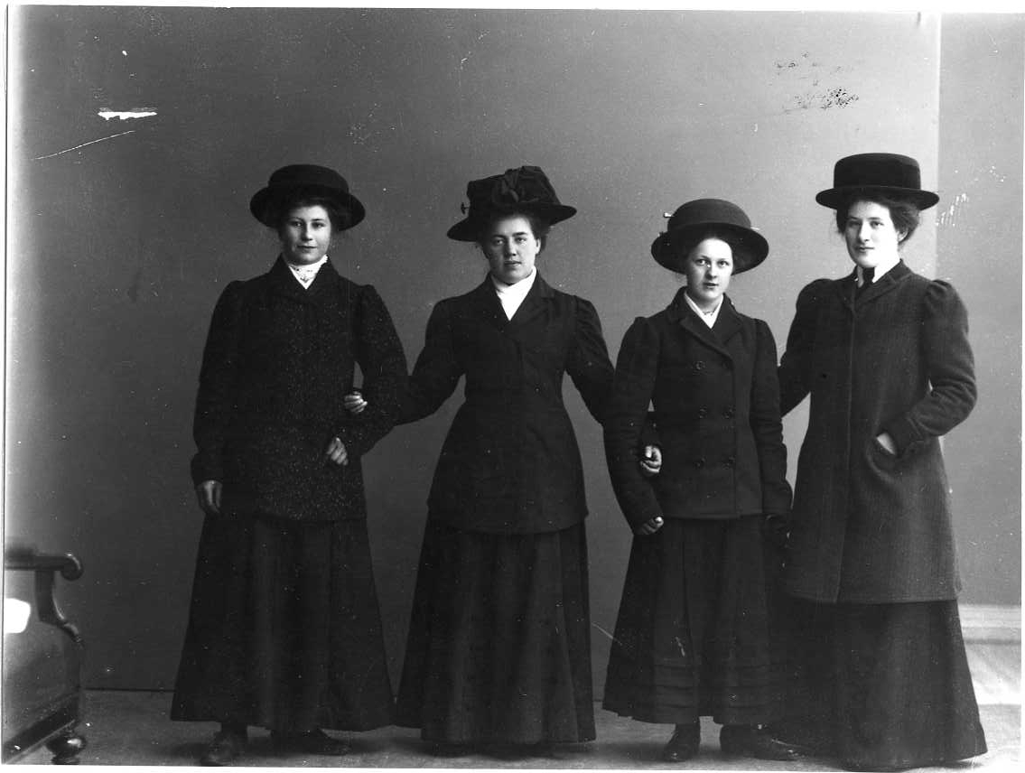 Gruppbild med fyra unga kvinnor i ytterkläder och hatt på huvudet. Från vänster (möjligen): Elvira Pettersson från Bohult, Edla Andersson från Aranäs, Elsa Tell samt Hanna Blixt från Aranäs.
