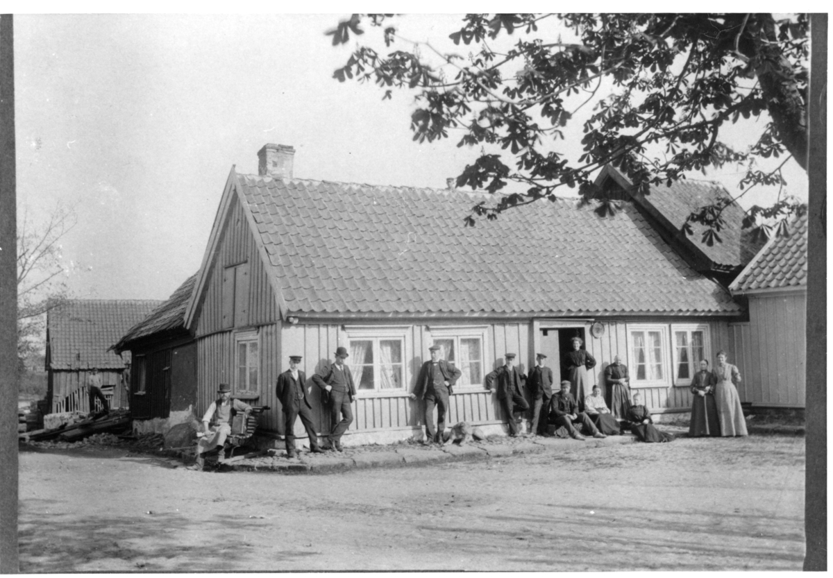 Törngrens gamla boningshus i hörnet av Krukmakaregatan och Lilla torg, rivet 1905. På trappan sitter C L Törngren och hans hustru Sofia. T v närmast trappan står sonen Hans. De tre stående männen , två av dem är guldsmeder, är söner till guldsmed C P Pettersson.