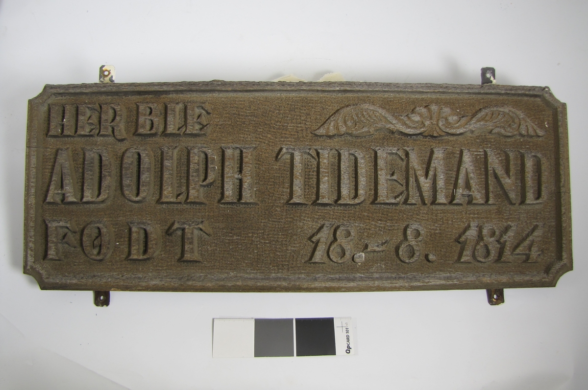 Plakett med teksten: "Her ble Adolph Tidemand født 16-.8. 1814"