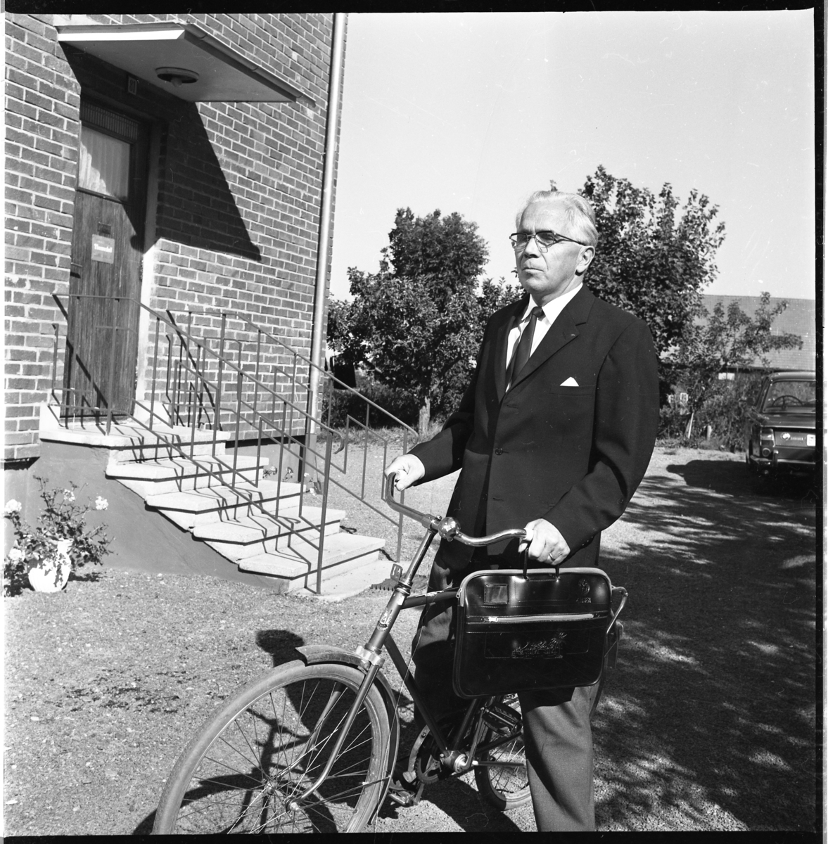 Pastor Robert Svensson står grensle över en cykel med en portfölj i ena handen.