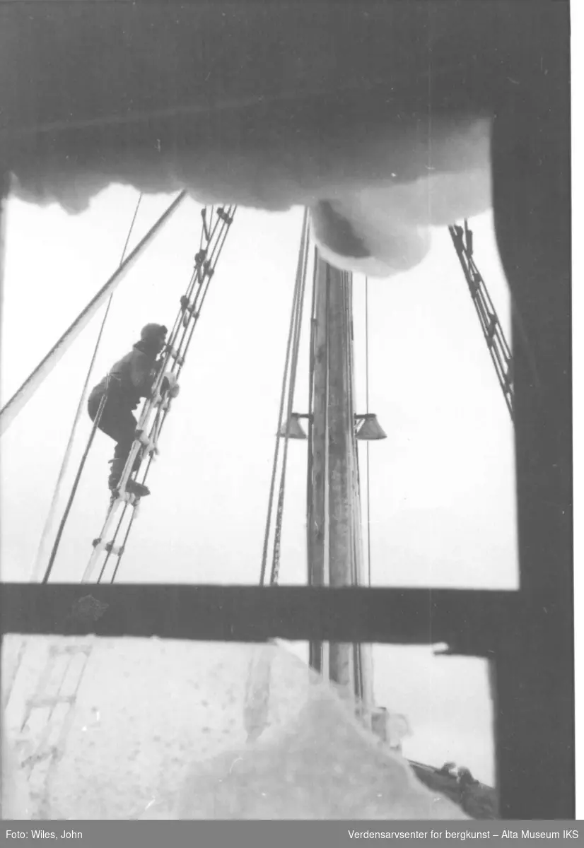 Mann klatrer i masten ombord på M/S Polis. Tatt fra inne i styrhuset.
