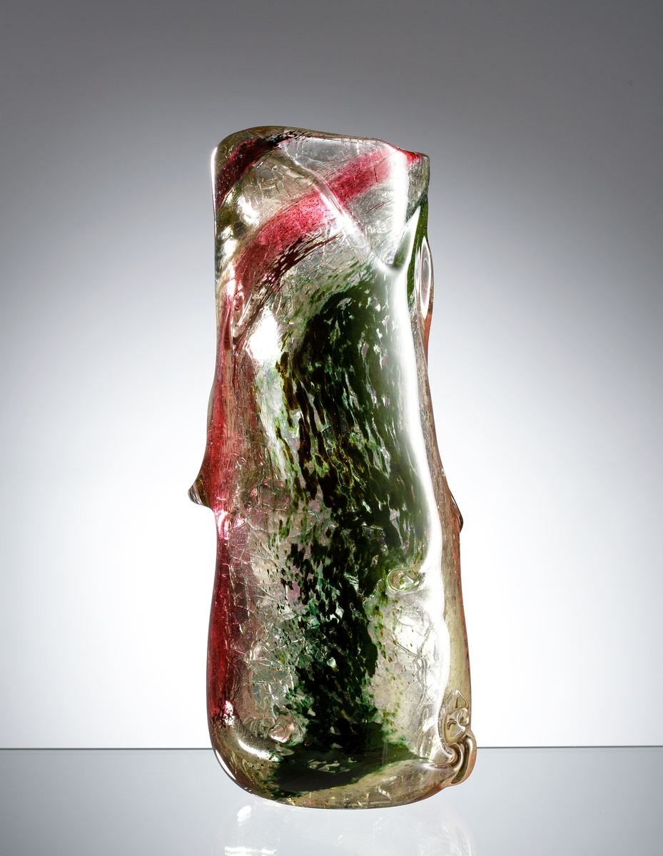 Vas som efterliknar stammen på ett träd. Klart glas med invälsade färger. Glaset är skrängt och utdraget med nopplika formationer.