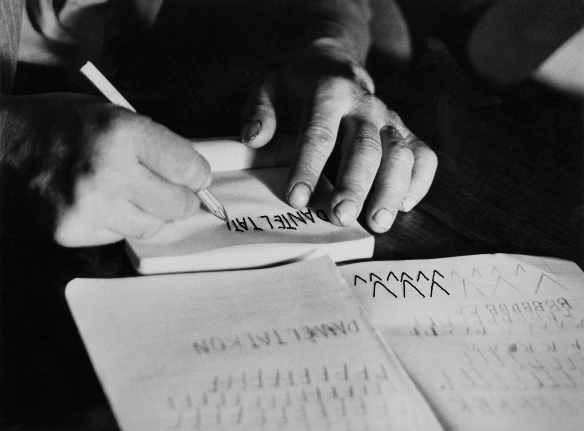 Expressens vuxenutbildning i Åseda 1963. En man sitter i en bänk och skriver bokstäver.