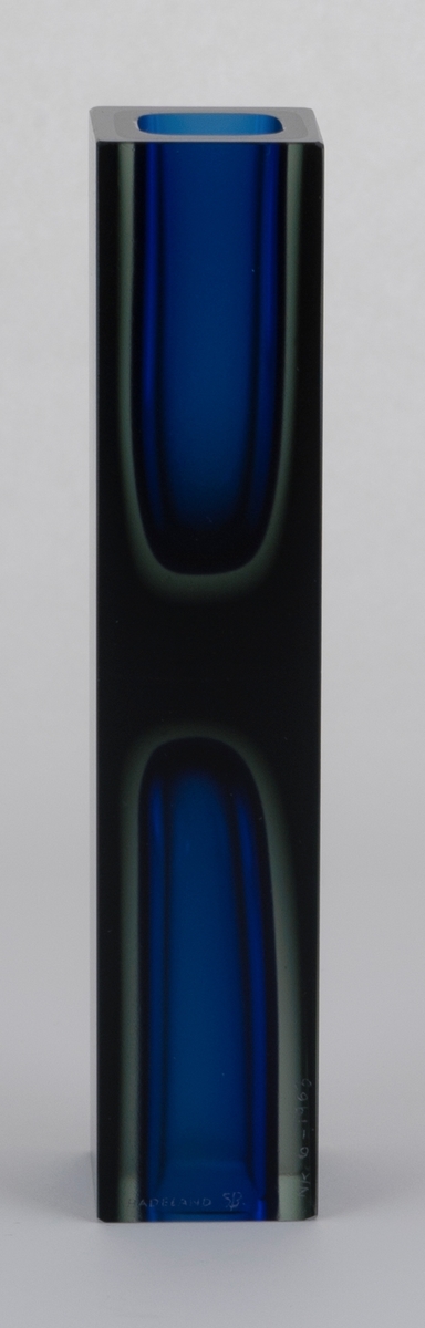 Høyreist rektangulær dobbelvase i gjennomskinnelig overfangsglass. Glassmassen består av tre lag, hvorav kjernen er kongeblå, det mellomste laget er lysegrått, og det ytterste er mørkegrått. Kortsidene har avrundede kvadratiske fordypninger, som gjør at begge sidene kan fungere som fot og korpus. Yttersidene er behandlet med sliping og har en matt glans.