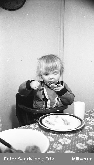 Pojke som sitter vid ett bord och äter kakor.