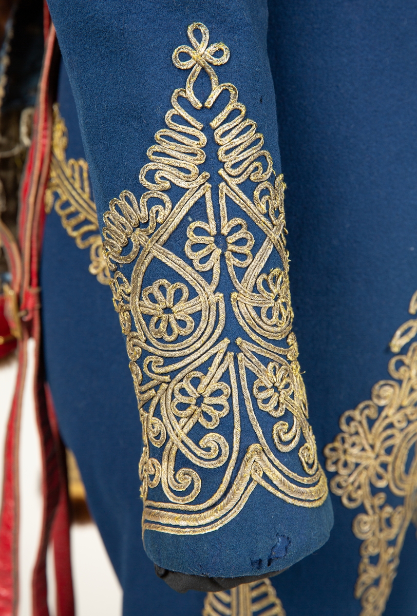Blå jakke til uniform med dekor av lissebrodri og runde sølvknapper.
