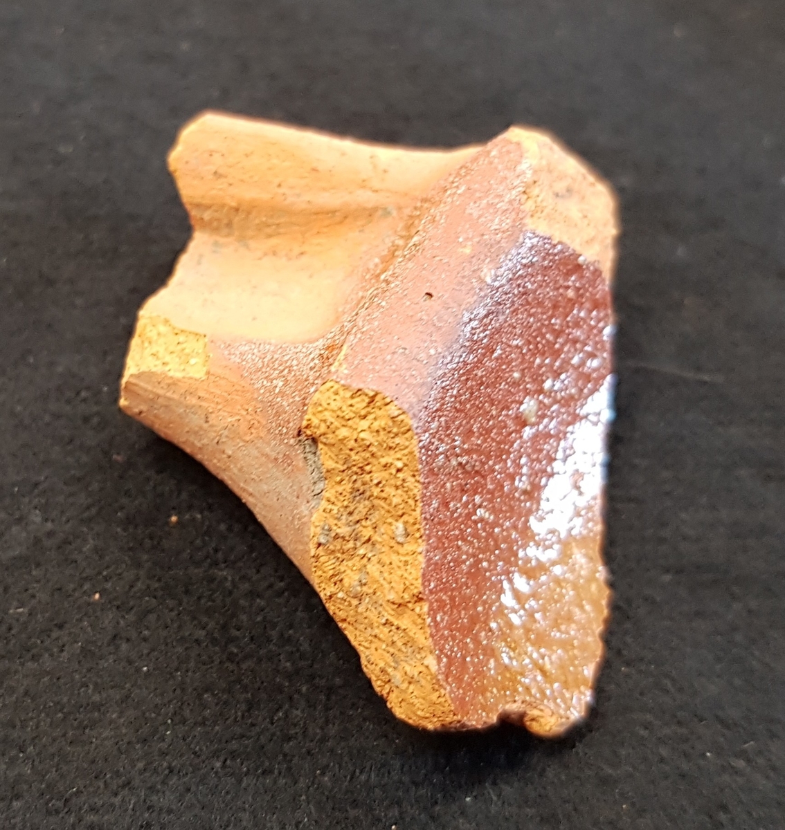 Fragment av stekpanna av lergods. Rödbrun glasyr. Infästningen av handtaget.

Funnen i anläggning S27.
Grävningsledaren ändrade sedan anläggningsbeteckningen i grävrapporten till K27.
Fynden kommer från en arkeologisk utgrävning/schaktövervakning av Brätte 1:8 ledd av Oscar Ortman 2018.