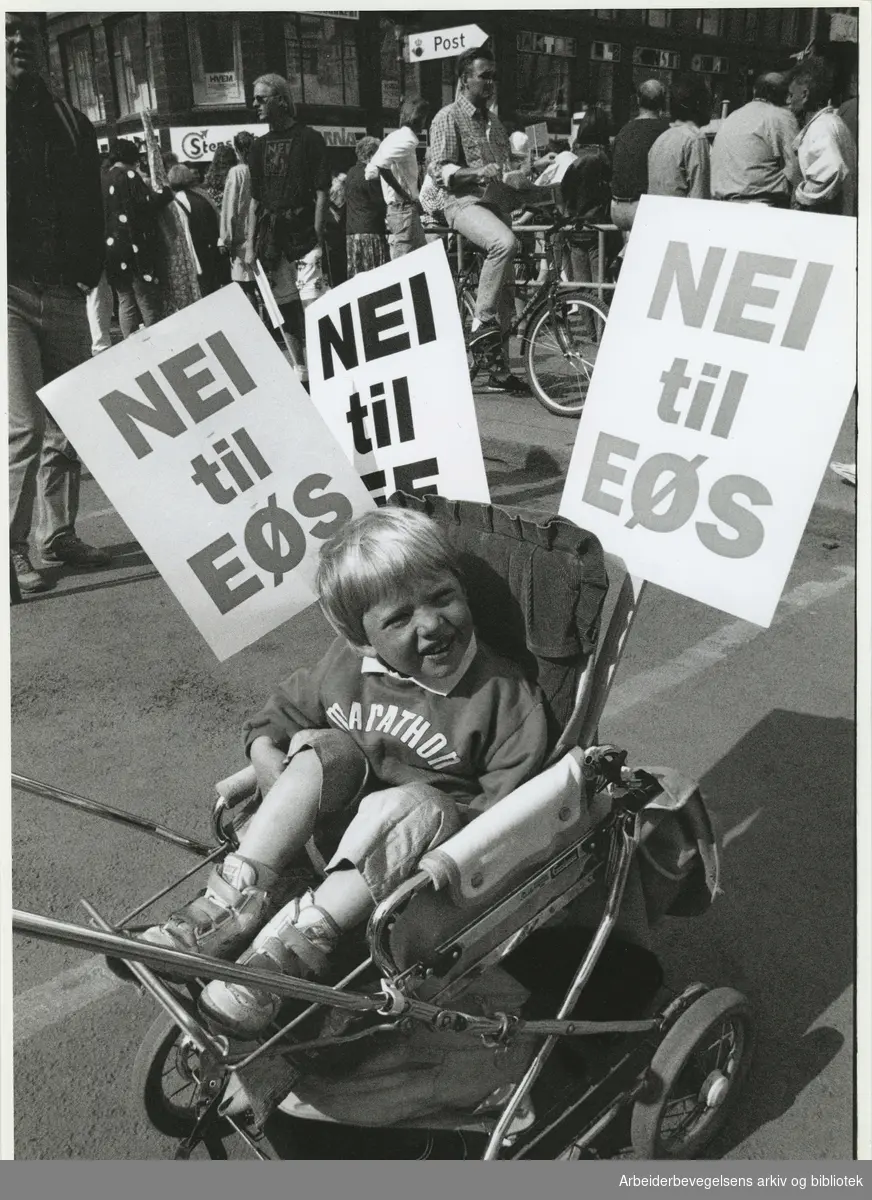 1. mai 1993, Oslo. Parole: Nei til Eøs. Tekst i avisen: Åsmund Stormoen (3) så ikke ut til å ha noe imot at barnevogna hans var parolestativ 1.mai.