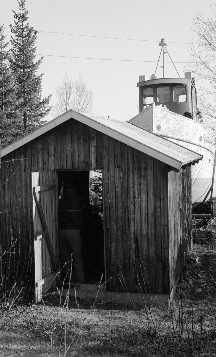 Sjøsetting av slepebåten «Trysilknut» fra Sørlistøa ved Osensjøen våren 1984. Osensjøen ligger i grensetraktene mellom Åmot og Trysil kommuner i Hedmark. Trysilknut ble bygd ved Glommens mek. Verksted i Fredrikstad i 1913-14, og ble da utstyrt med dampmaskin. Først i 1957-58 ble slepebåten ombygd til dieseldrift. De første åra hadde Trysilknut vinteropplagssted i Hundsvika i Valmen, der den med stort besvær, og slett ikke hver vinter, ble dratt på land for mønjing. I 1939 kjøpte Glomma fellesfløtingsforening den 21 dekar store eiendommen Sørlistøa, mellom innsjøens vestre bredd og bygdevegen. Ordet stø brukes om steder der man har dratt båter på land, og på Sørlistøa bygde Fellesfløtingsforeningen en slipp for Trysilknut og de andre båtene som ble brukt på Osensjøen. Mens de mindre båtene ble vinterlagret i et båthus, lå Trysilknut øverst på slippen, under åpen himmel. Herfra ble den firt ned på ei skinnegående vogn om våren og trukket opp igjen om høsten. Under sjøsetting og opptak ble det brukt en vinsj, som sto inne i det drøyt 11 kvadratmeter store huset i forgrunnen.