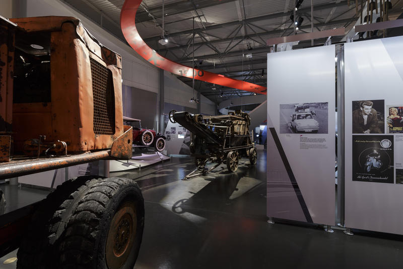 Bildet er fra utstillingen Tida og vegen. Bildet viser tekstplansjer, maskiner og en bil.